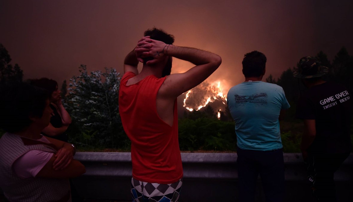 اهالي قرية ميغا فونديرا البرتغالية ينظرون الى الحرائق التي تجتاح قريتهم ( الصورة نقلاً عن afp)