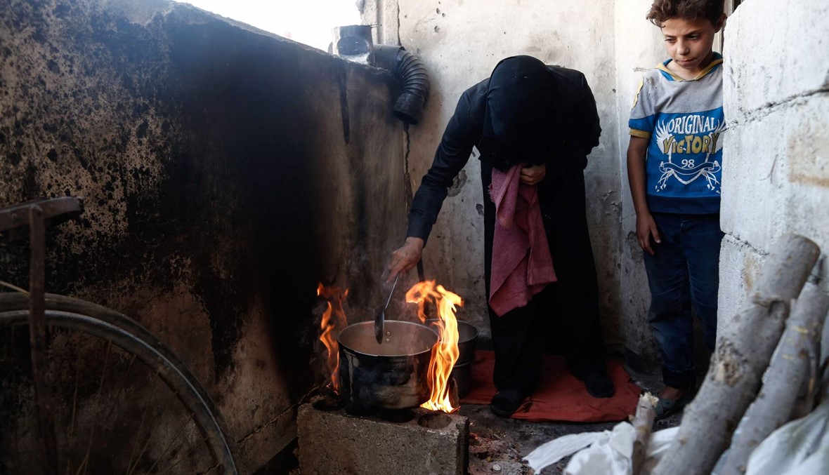امرأة تطهو الطعام على الحطب في ظل ارتفاع أسعار الغاز في منطقة دوما السورية. (الصورة نقلاً عن أ. ف. ب)