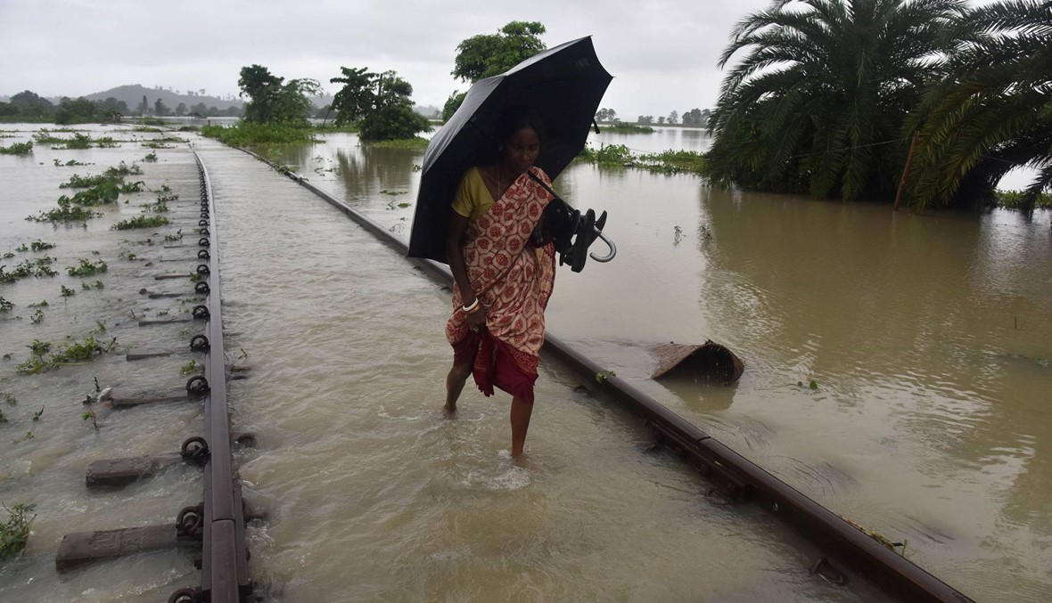 سيّدة هنديّة تسير على سكّة حديد غمرتها المياه بعد الفيضانات (الصورة نقلاً عن أ.ف.ب)