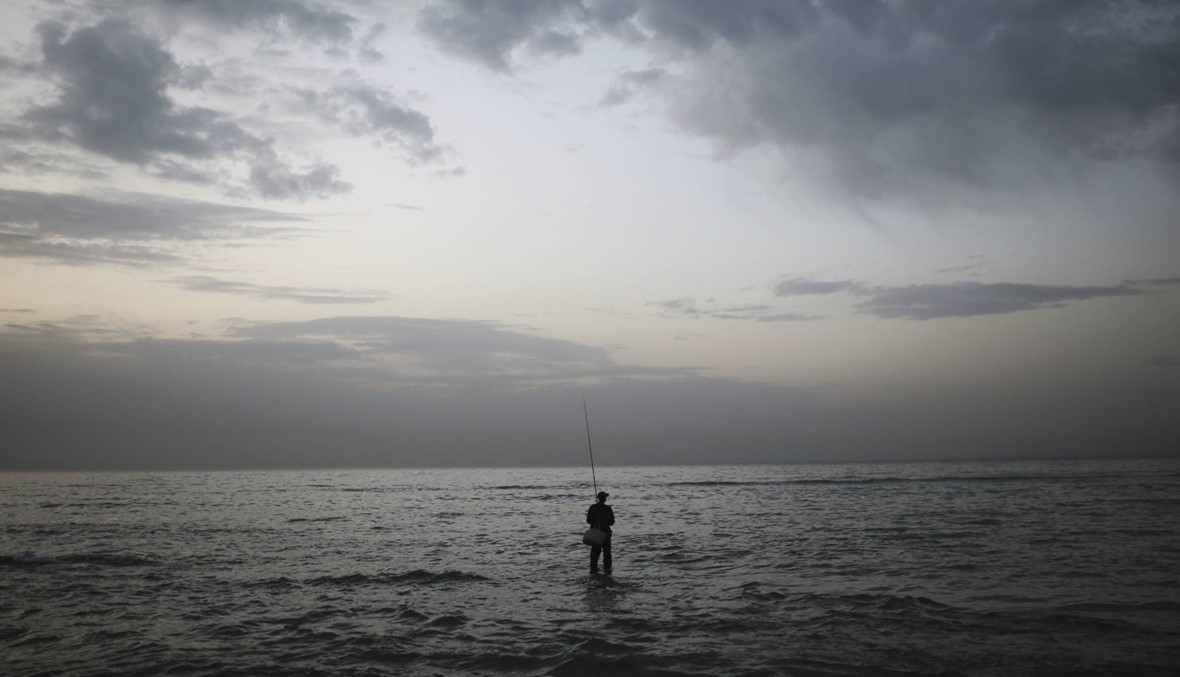 صياد مغربي يصطاد السمك على شاطئ بلدة أصيلة الساحلية (أ ب).