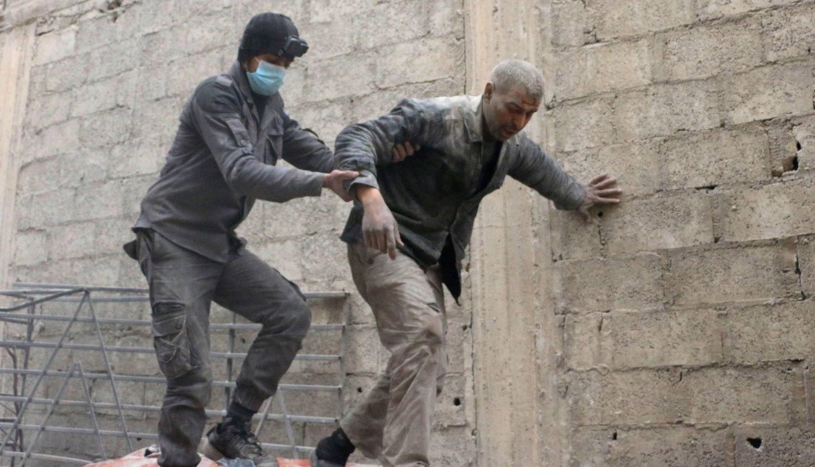 عمال الاغاثة يساعدون رجلاً في الغوطة السورية بعد القصف الذي طال المنطقة (أ ف ب).