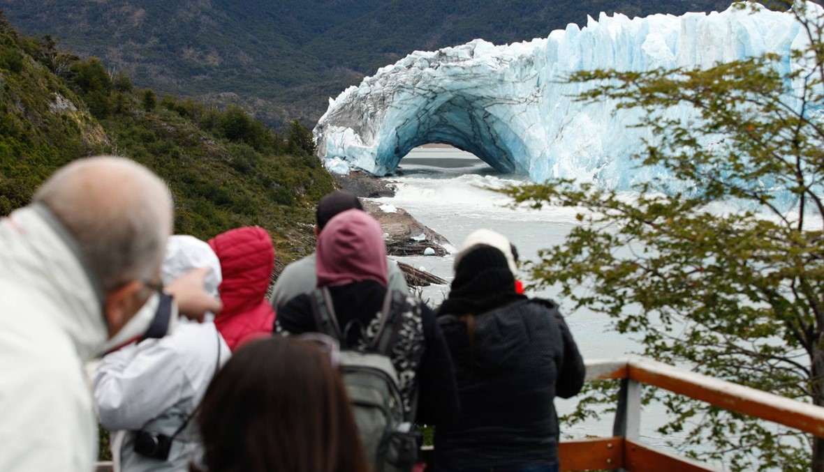 سياح يلتقطون صورا لجبل "بيريتو مورينو" الجليدي في حديقة "لوس غلاسياريس" الوطنية في مقاطعة "سانتا كروز" الأرجنتينية في 11 آذار 2018. قوس من الجليد تشكّل بين الجبل الجليدي وضفة بحيرة "أرجنتينو"، وبدأ ينهار في الماء السبت 10 آذار، في عرض طبيعي لا يحصل سوى مرة واحدة فقط كل سنوات عدة. مثل هذه الأقواس تتش