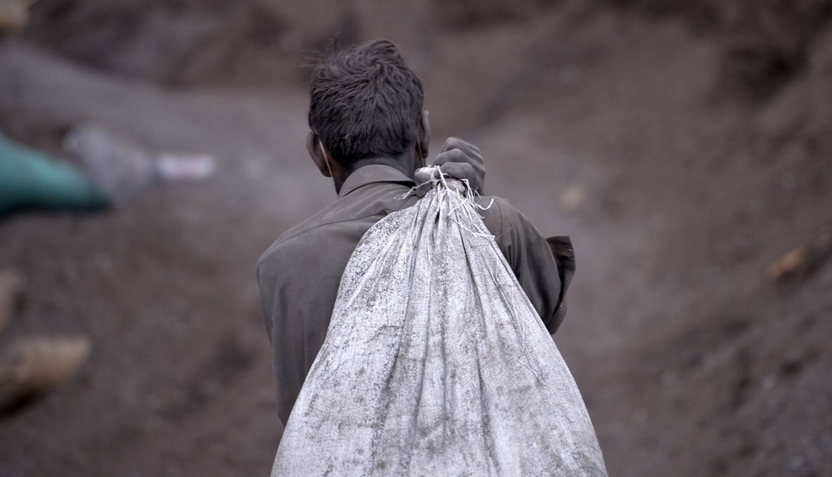 فتى باكستاني يحمل كيساً من الفحم في يوم عيد العمّال (أ ف ب).