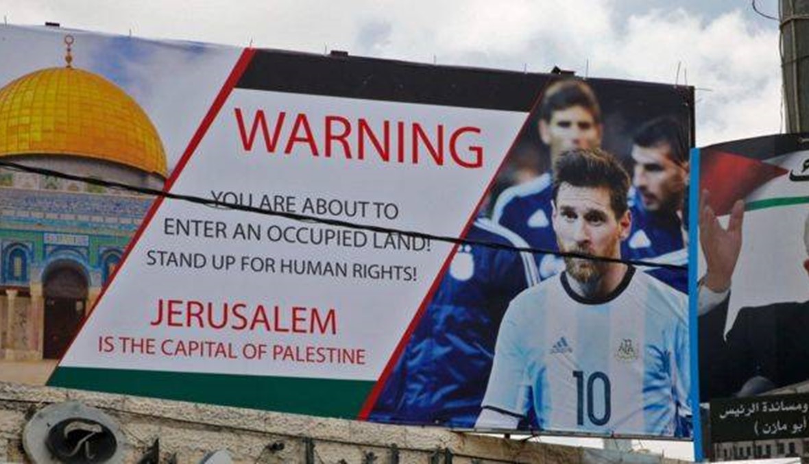 صورة ميسي على لافتة في الضفة الغربية تدعو لإلغاء المباراة في القدس (إ ف ب).