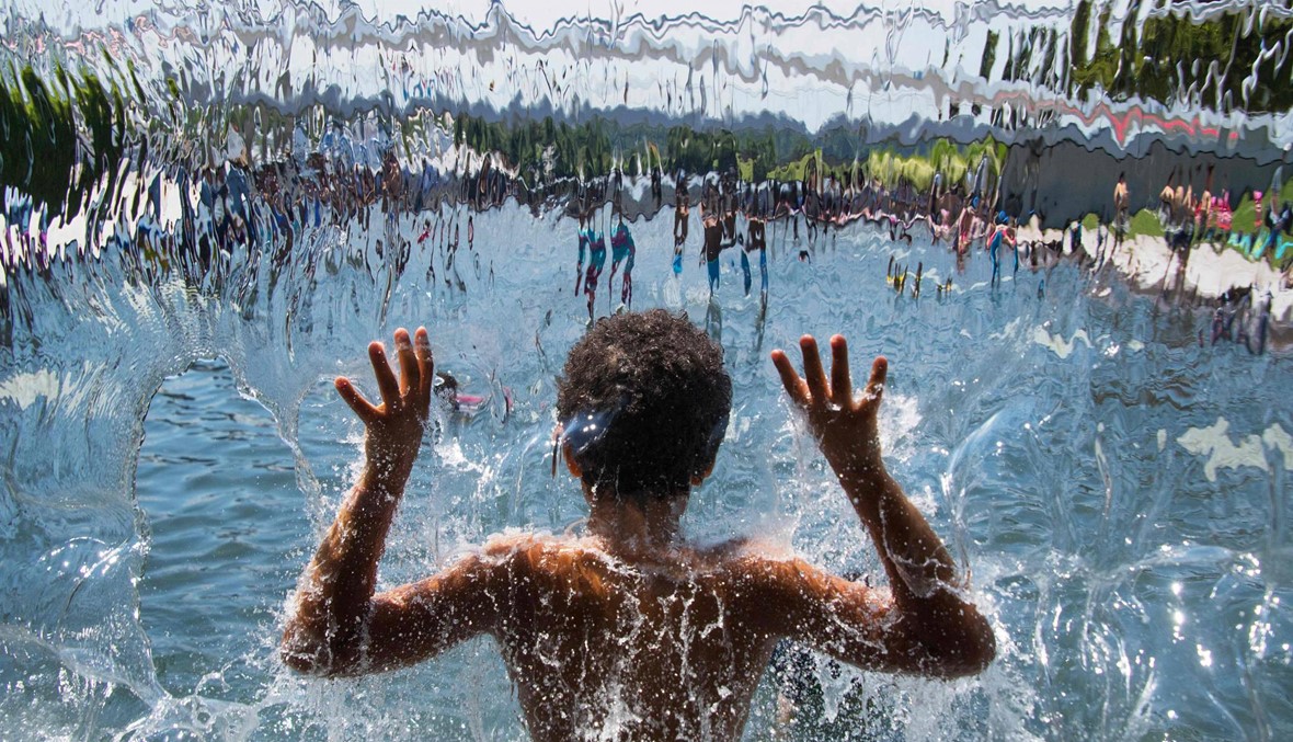 فتى يلهو في بركة سباحة نتيجة ارتفاع درجات الحرارة في واشنطن (أ ف ب).