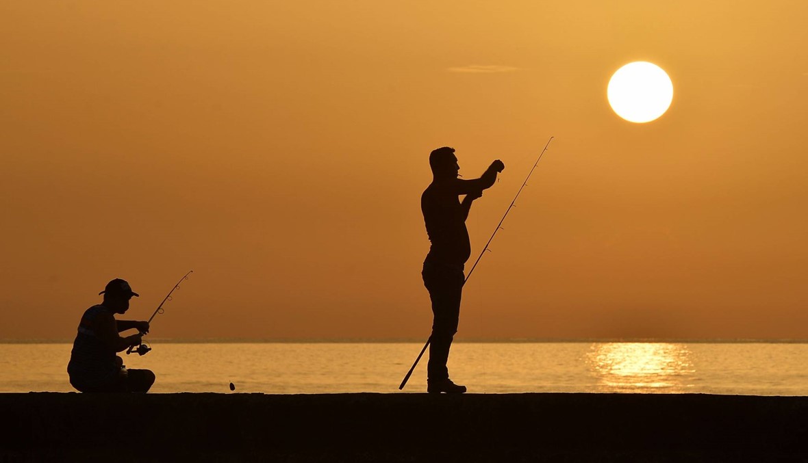 شابان يمارسان هواية الصيد عند مغيب الشمس على شاطئ هافانا (أ ف ب).