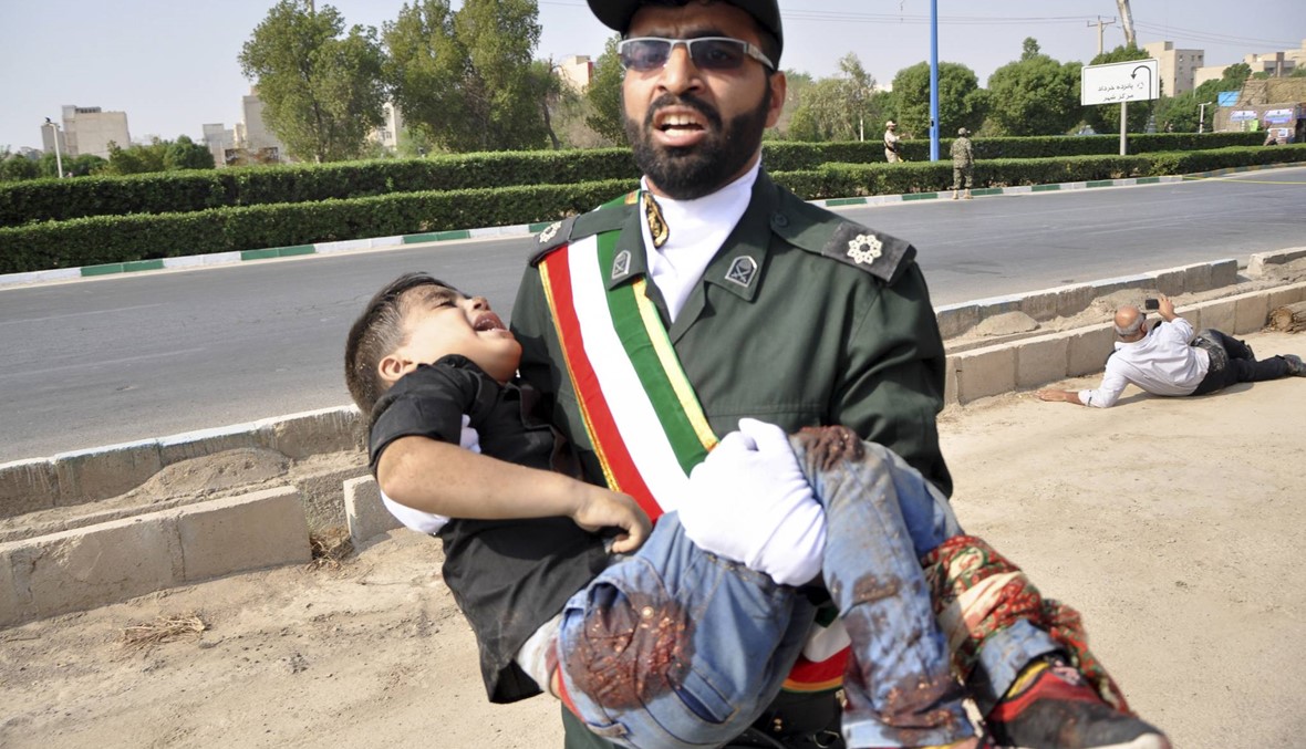 عنصر في الحرس الثوري الأيراني يحمل فتى مصاباً بطلق ناري بعد هجوم الأهواز (أ ب).