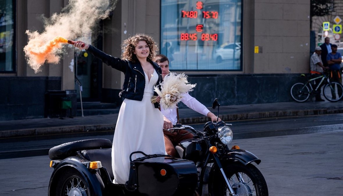 ثنائي تزوج حديثًا يقف خلال جلسة تصوير بالقرب من مكتب للصرافة في موسكو (3 أيلول 2020، أ ف ب).