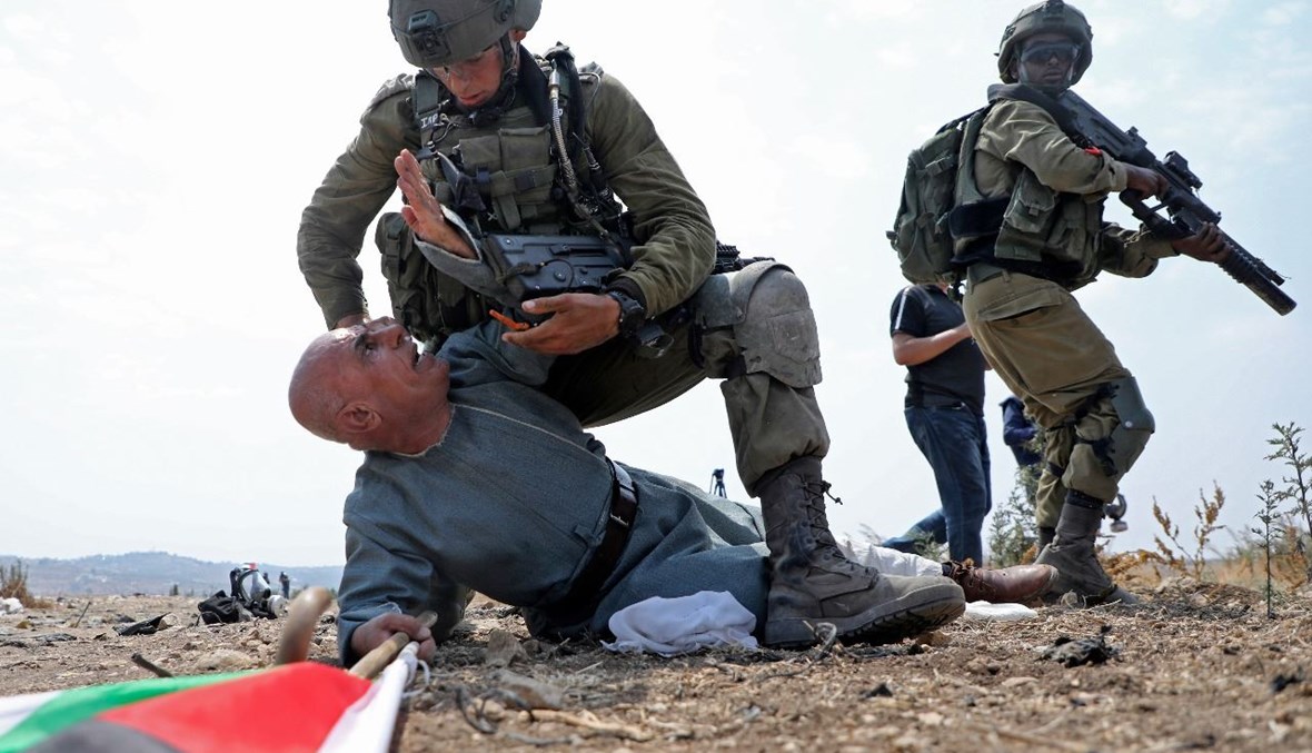 جندي إسرائيلي يثبت ارضا خيري خلال تظاهرة ضد التوسع الاستيطاني الإسرائيلي في قرية جبارة جنوب طولكرم في الضفة الغربية المحتلة (1 أيلول 2020، أ ف ب).
