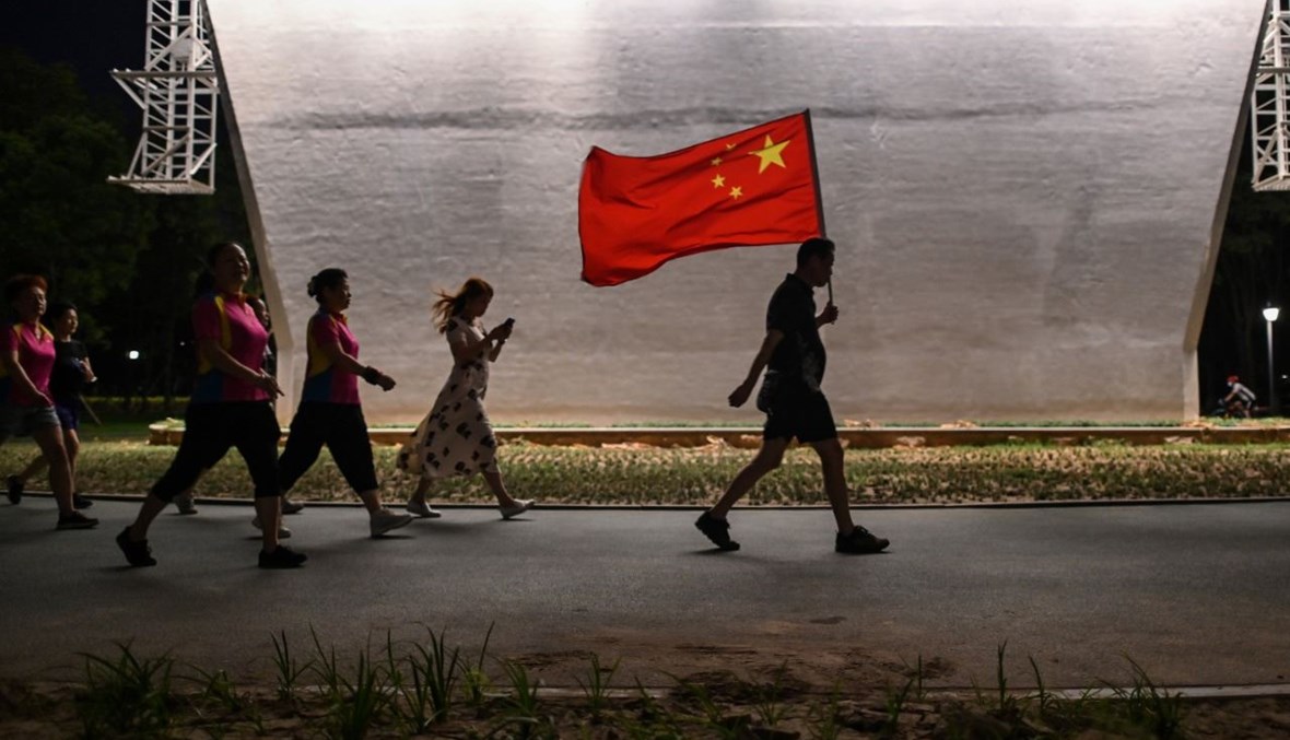 رجل يحمل العلم الصيني في حديقة بجوار نهر يانغتسي في ووهان (4 أيلول 2020، أ ف ب).