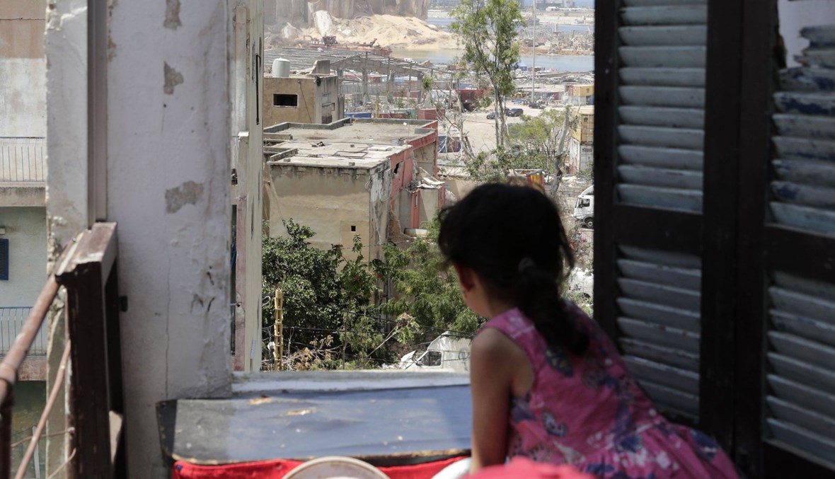 A girl stands at the window of her apartment overlooking the destroyed silo on at Beirut's port, Aug. 11, 2020. (AFP Photo)