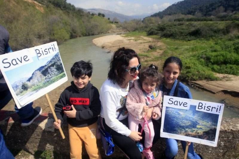 A Lebanese family holds placards during a protest against the Bisri dam project, in the Bisri Valley, 58 kilometers (36 miles) southeast of Beirut, Lebanon. (AP Photo)