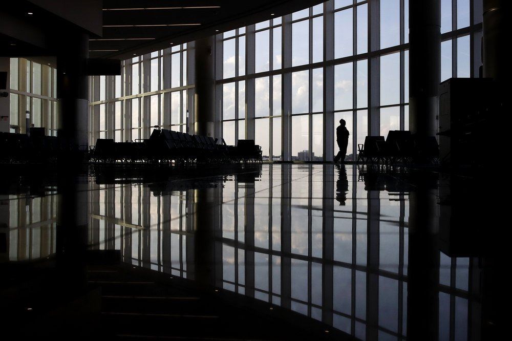 FILE - In this June 1, 2020 file photo, a woman looks through a window at a near-empty terminal at an airport in Atlanta. (AP Photo)