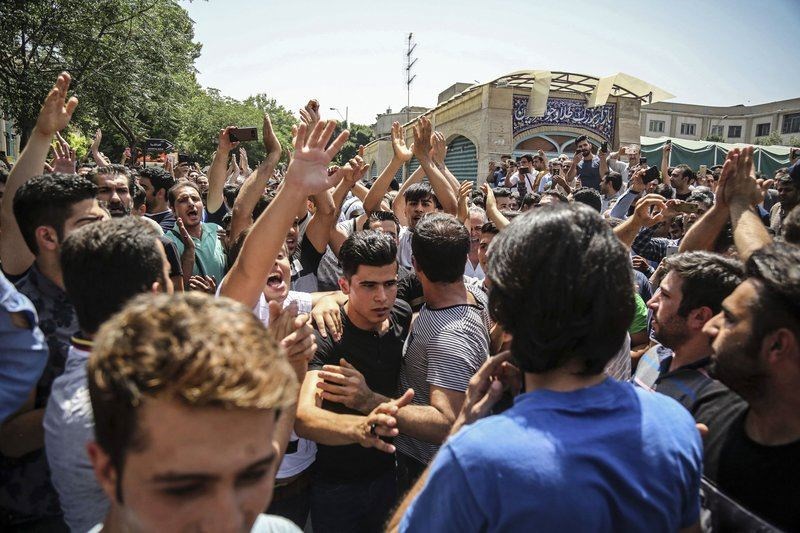 FILE - In this June 25, 2018 file photo, a group of protesters chant slogans at the main gate of the Old Grand Bazaar, in Tehran, Iran. (AP Photo)