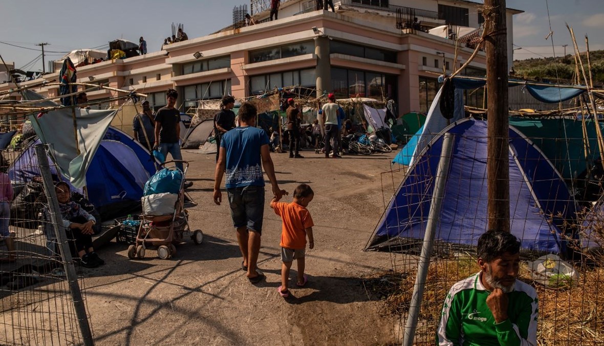 مهاجرون يسيرون بالقرب من مخيم موقت جديد في جزيرة ليسبوس (14 أيلول 2020، أ ف ب). 