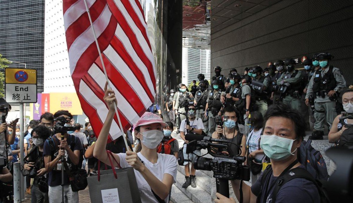 FILE - In this July 4, 2020, file photo, a woman carries an American flag during a protest outside the U.S. Consulate in Hong Kong. (AP Photo)