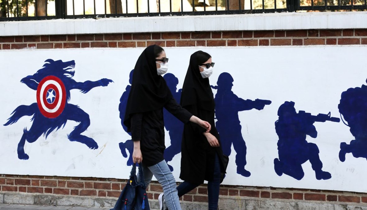 امرأتان تمران بالقرب من لوحة جدارية مرسومة على الجدران الخارجية للسفارة الأميركية السابقة في طهران (20 أيلول 2020، أ ف ب). 