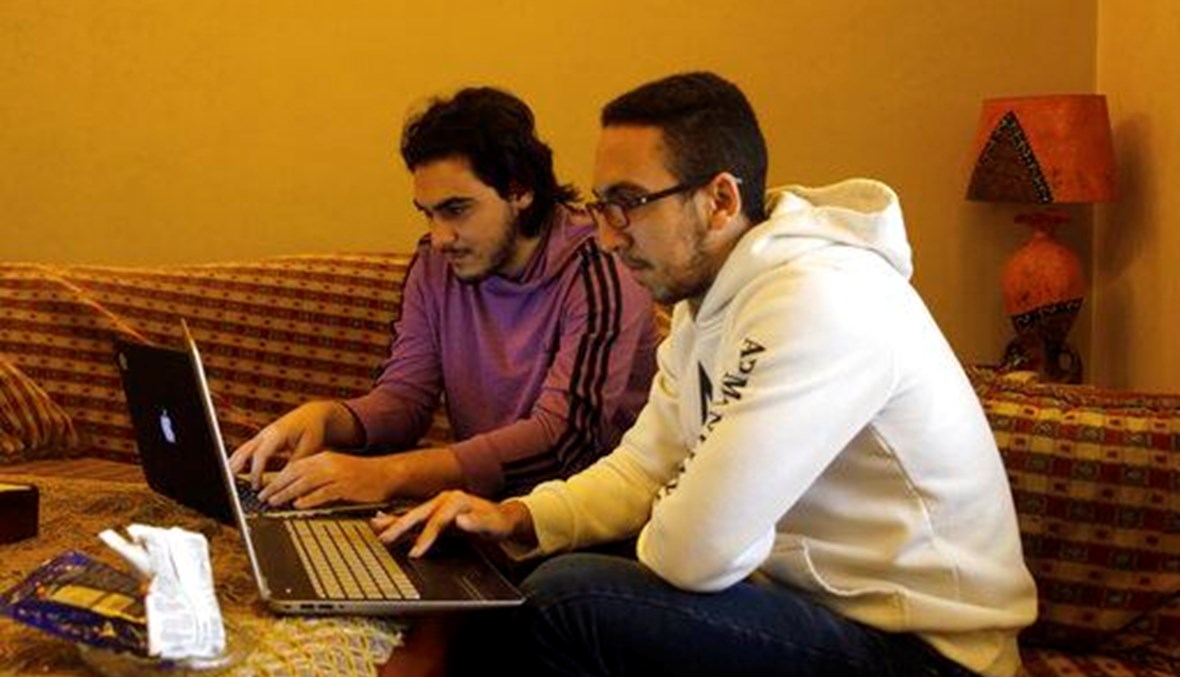 Issa Bazazo, left, and his friend Muhammad Jardani use their computers to take an online class, at Bazazo's house in Beirut, Lebanon, Thursday, March 26, 2020. (AP Photo)