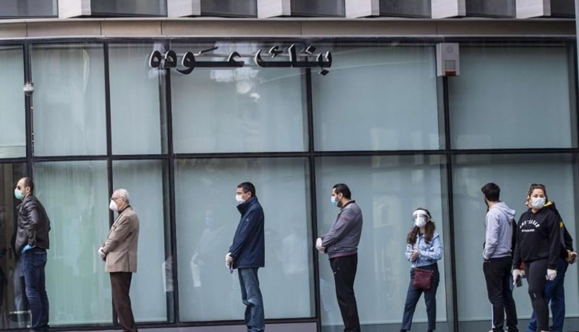Clients wearing protective masks line up to use ATM machines outside a closed bank in Beirut, Lebanon. (AP Photo)
