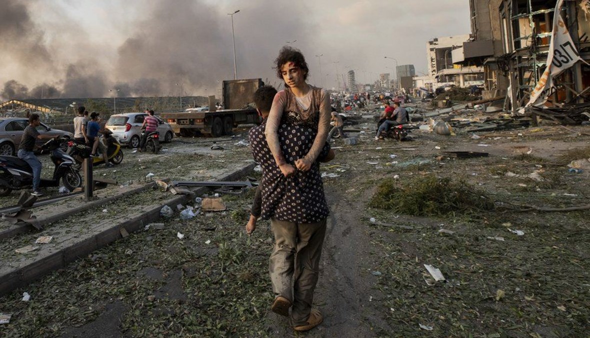 In this Aug. 4, 2020 file photo, Hoda Kinno, 11, is evacuated by her uncle Mustafa, in the aftermath of a massive explosion at the port in Beirut, Lebanon. (AP Photo) 