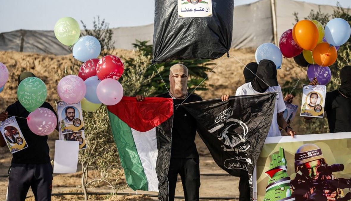 فلسطينيون من لجان المقاومة قرب رفح بقطاع غزة يهيئون بالونات لإطلاقها حاملة شعارات نحو إسرائيل.   (أ ف ب)