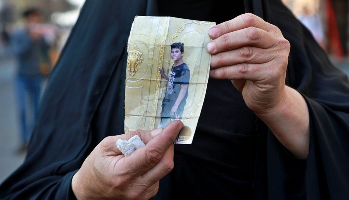 A woman holds a picture of her a missing son during anti-government protest in Baghdad, Iraq, Sunday, Feb. 23, 2020. (AP Photo)