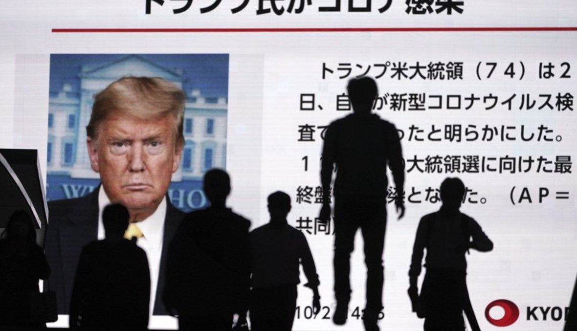 People walk past a screen showing the news report that President Donald Trump has tested positive for the coronavirus, Friday, Oct. 2, 2020, in Tokyo. (AP Photo)