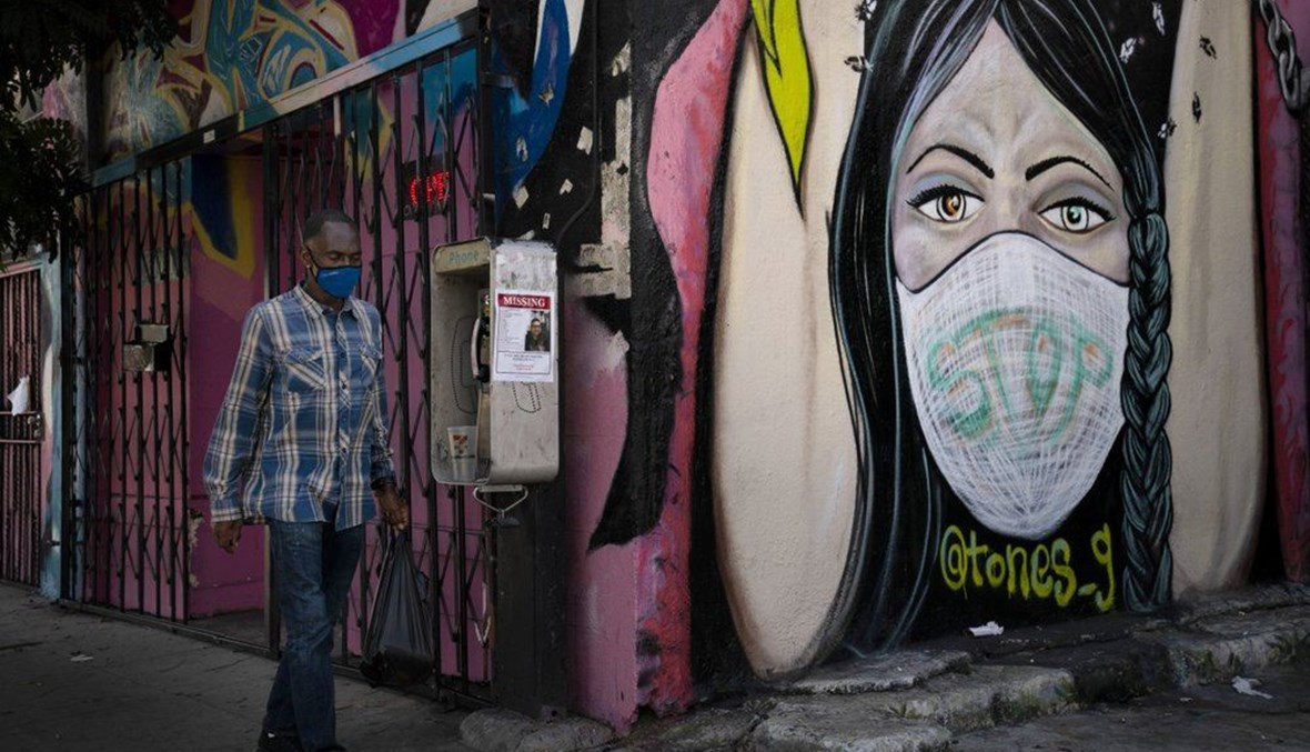  In this Oct. 1, 2020, file photo, a man wearing a face mask walks past a mural in South Central Los Angeles. (AP Photo)