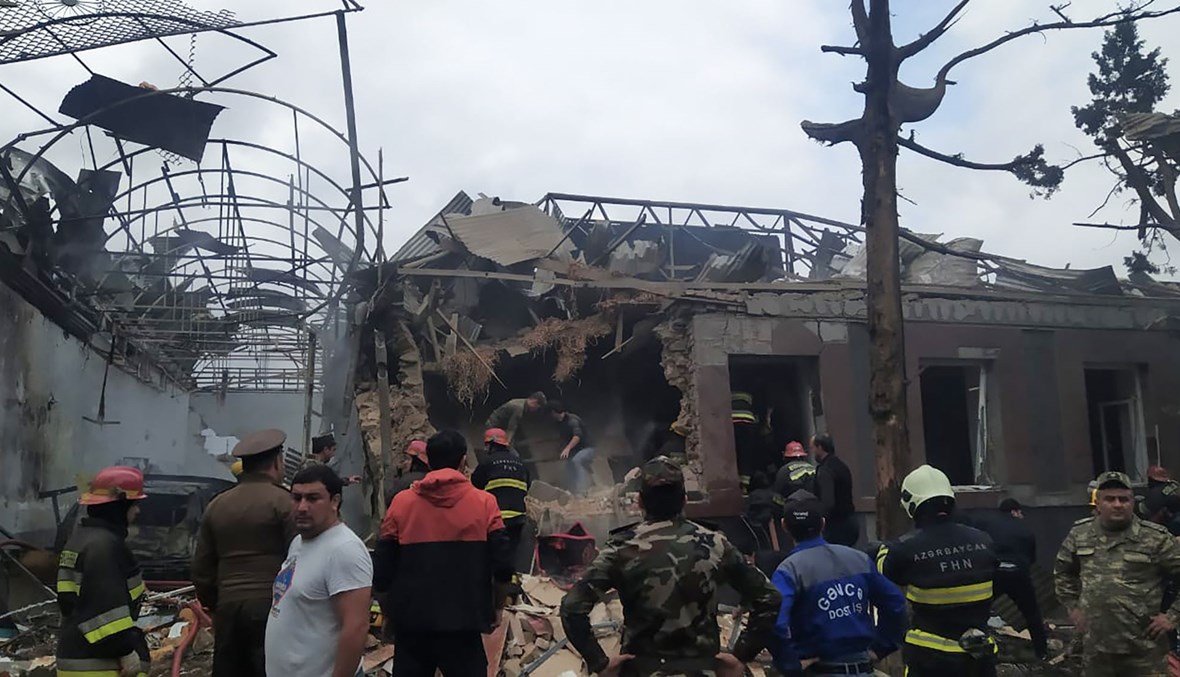موظفو طوارئ في منطقة متضررة في مدينة كنجه في أعقاب قصف صاروخي أرميني عليها (4 ت1 2020، أ ف ب). 