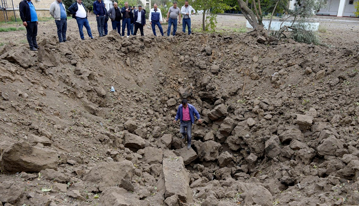 أشخاص وقفوا عند حفرة نجمت عن قصف صاروخي أرميني في بلدة بيلاجان (4 ت1 2020، أ ف ب). 