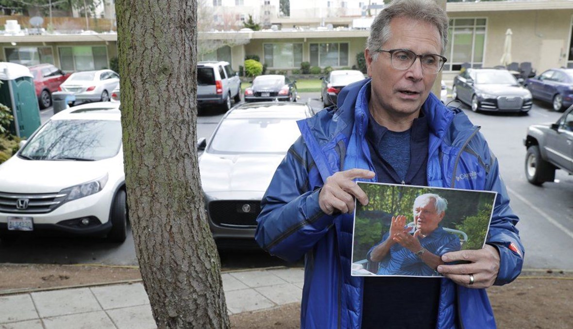Scott Sedlacek poses while holding a photo of his father, Chuck, outside Life Care Center in Kirkland. (AP Photo)