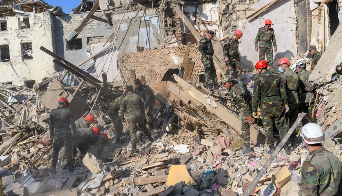 رجال إنقاذ يبحثون عن ناجين في ركام مبنى تعرض للقصف في مدينة كنجه بأذربيجان (11 ت1 2020، أ ف ب). 