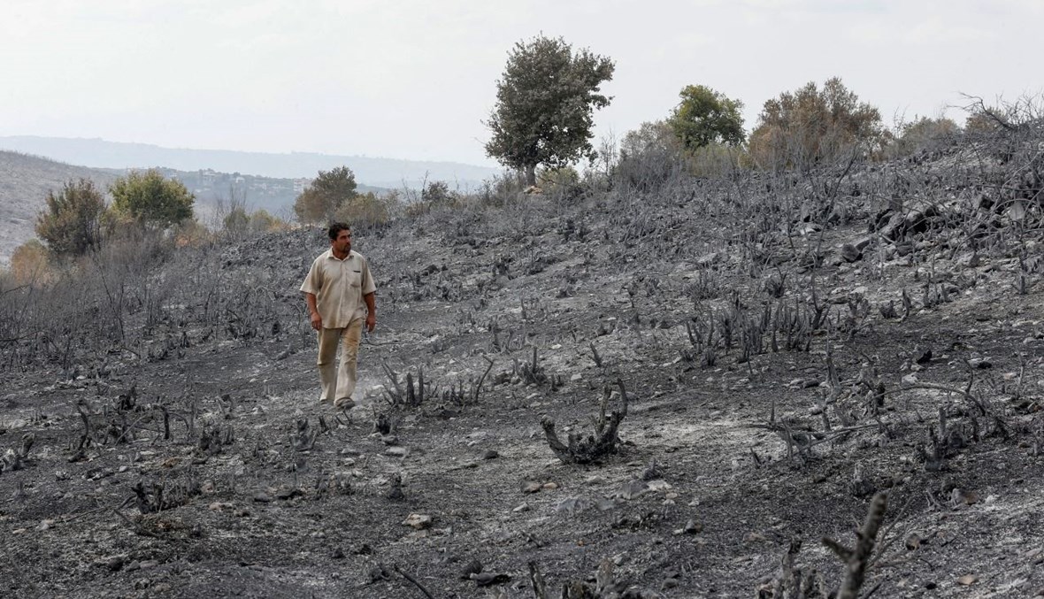 رجل سوري يتفقد منطقة التهمتها النيران في ريف طرطوس غرب سوريا (11 ت1 2020، أ ف ب). 
