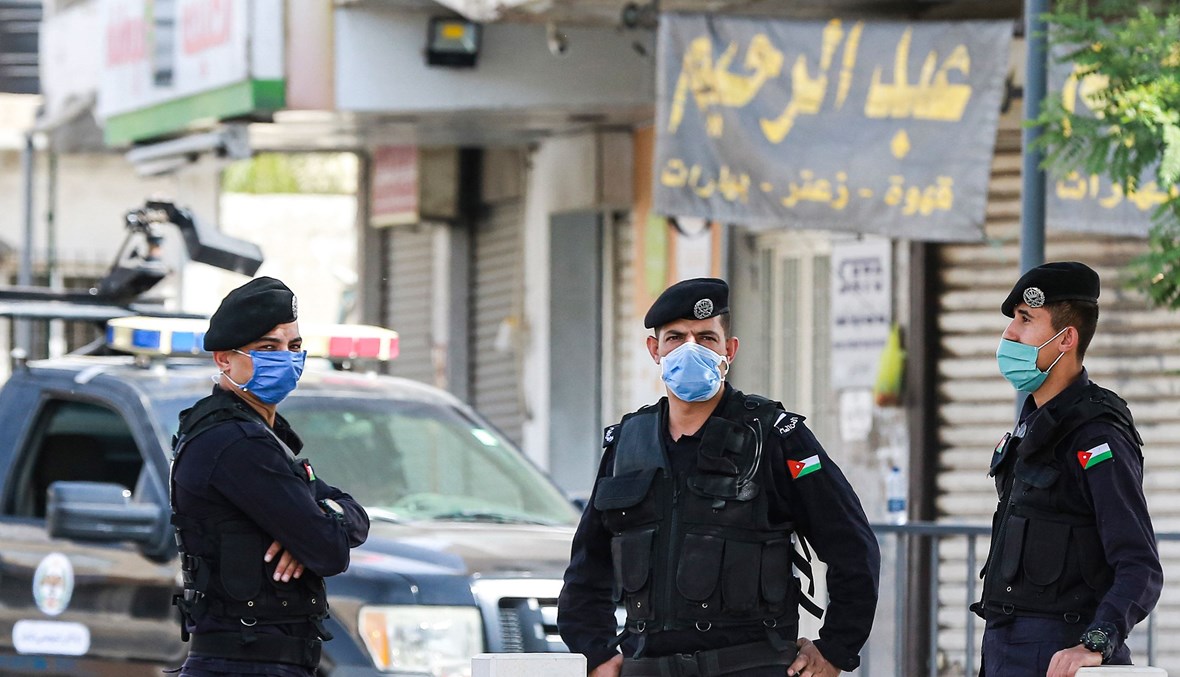 رجال شرطة أردنيون وقفوا عند نقطة تفتيش خلال تطبيقهم الإغلاق في عمان (9 ت1 2020، أ ف ب). 