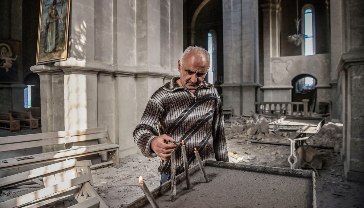 رجل يضيء شمعة في كاتدرائية "المخلّص الإلهي" التي طالها القصف الأذربيجاني في كراباخ (أ ف ب).