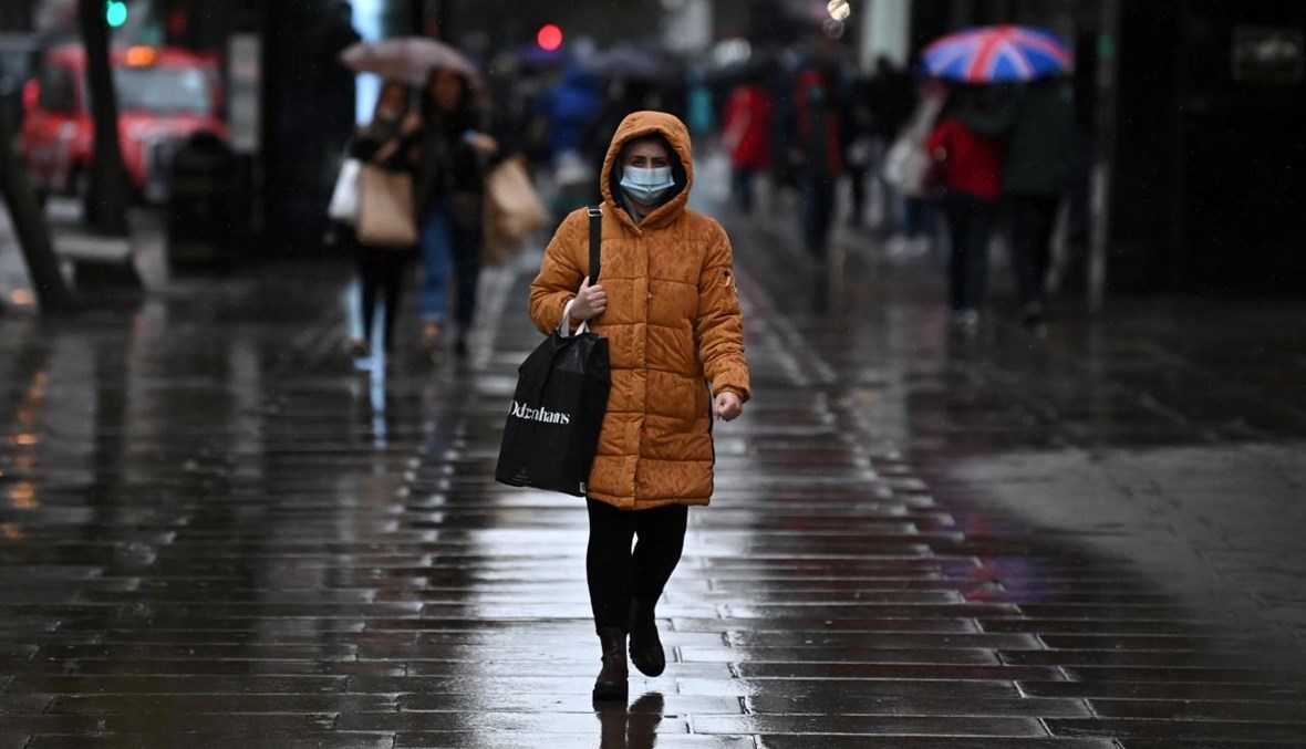 أشخاص يمشون في شارع أكسفورد بلندن في يوم ماطر (13 ت1 2020، أ ف ب). 