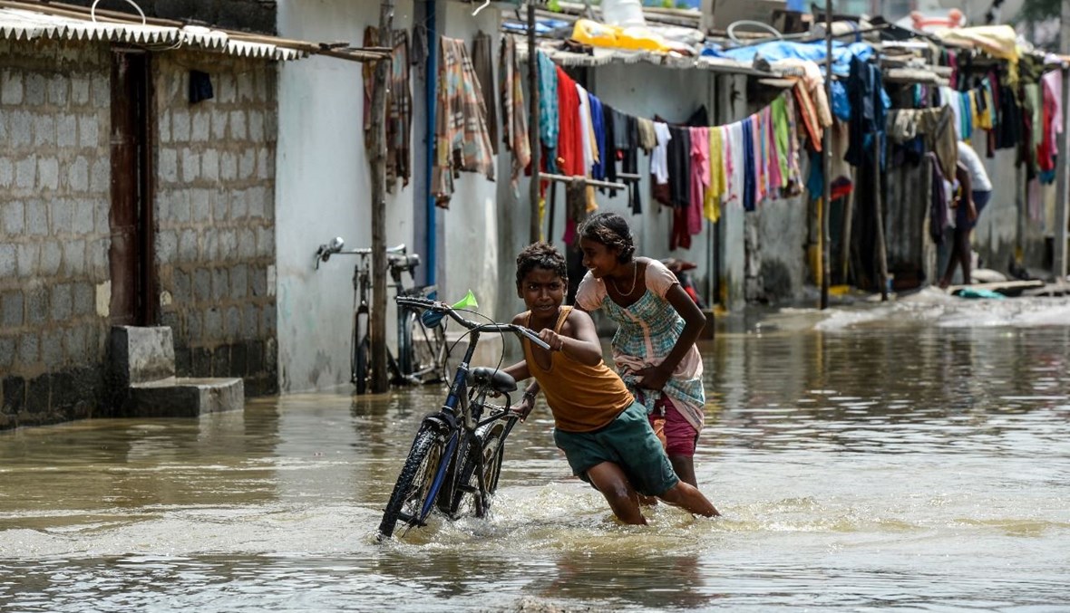 ولدان يدفعان دراجة في شارع اغرقته السيول في حيدر اباد (15 ت1 2020، أ ف ب). 