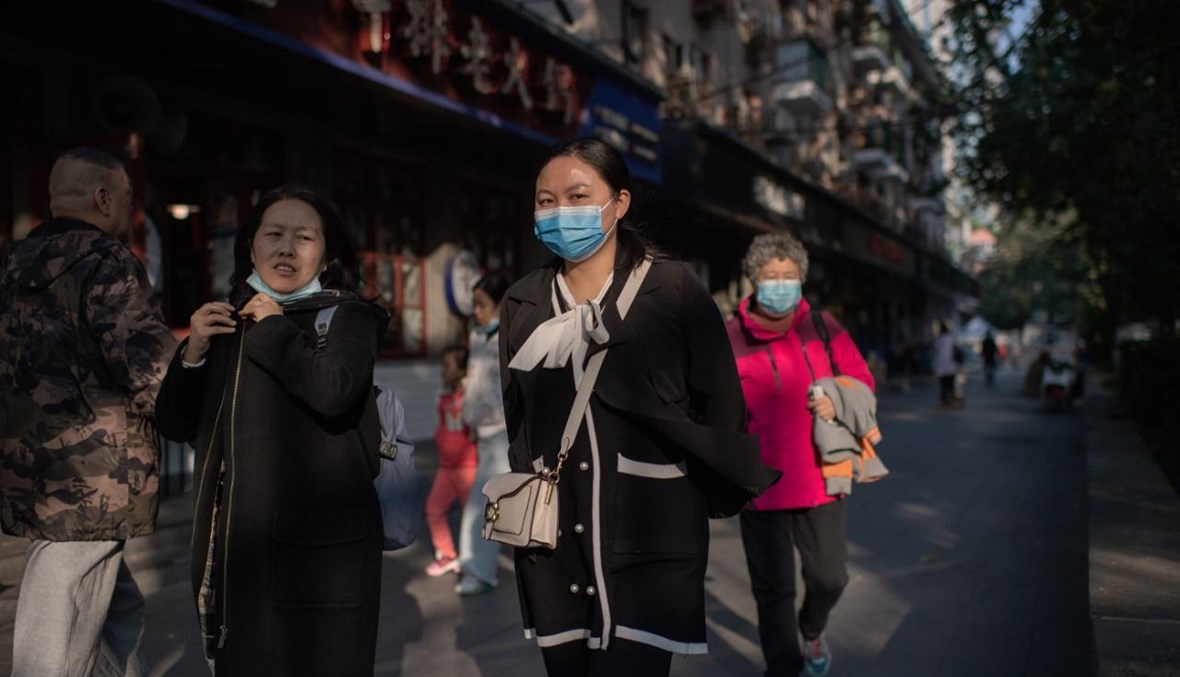 نساء يمشين في أحد الشوارع في بيجينغ (19 ت1 2020، أ ف ب). 