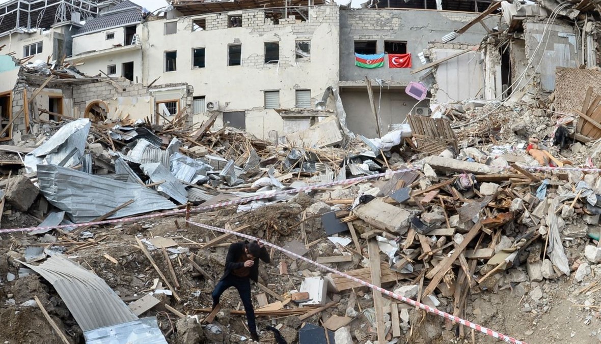 رجل يقف وسط أنقاض مبان مدمرة في منطقة سكنية في مدينة غنجة بأذربيجان من جراء القصف عليها (22 ت1 ، أ ف ب). 