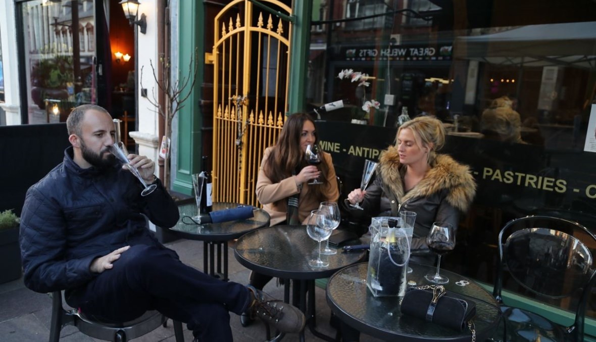 أشخاص يتناولون المشروبات في الهواء الطلق خارج بار في وسط كارديف ببريطانيا (23 ت1 2020، أ ف ب). 