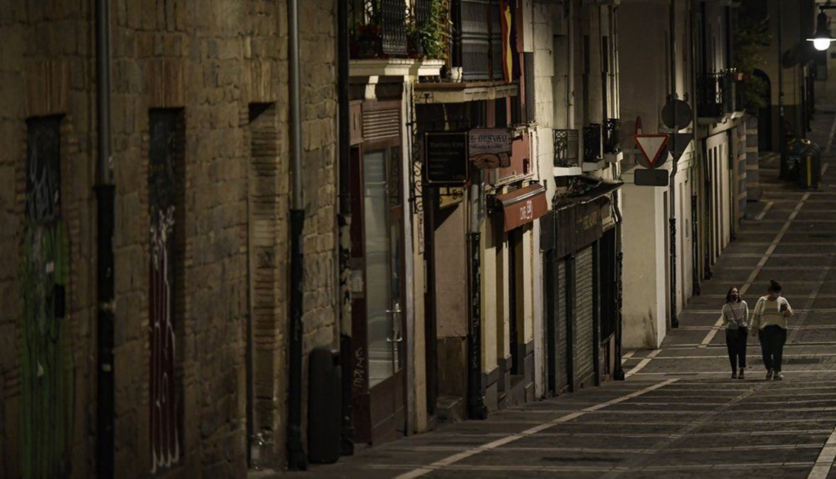 شخصان يمشيان في شارع مقفر في بامبلونا شمال إسبانيا (24 ت1 2020، أ ب). 