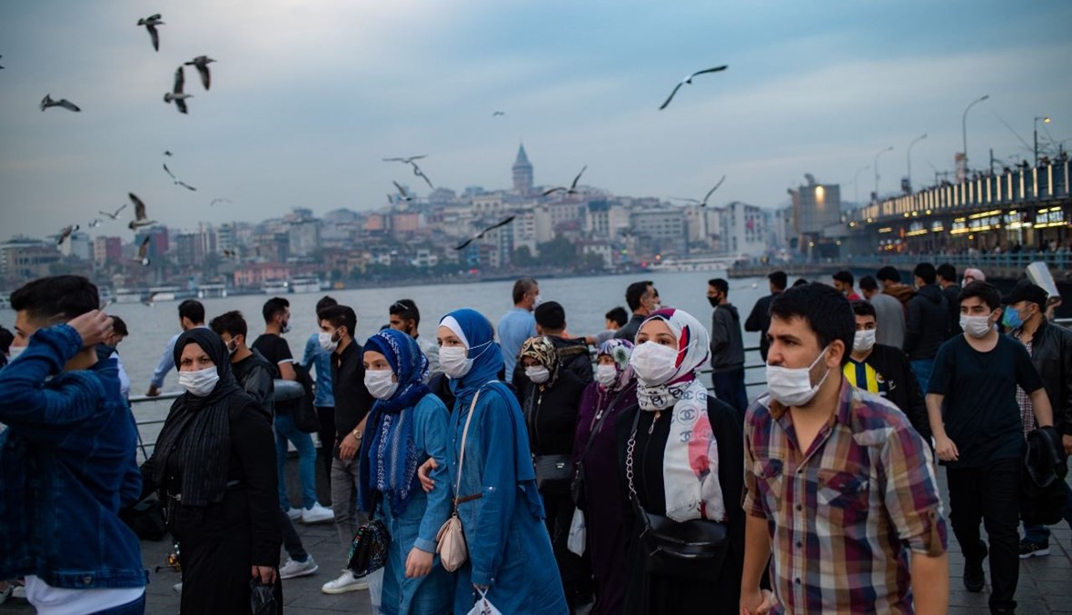 أشخاص يتمشون بالقرب من جسر غلطة في اسطنبول (25 ت1 ، أ ف ب). 