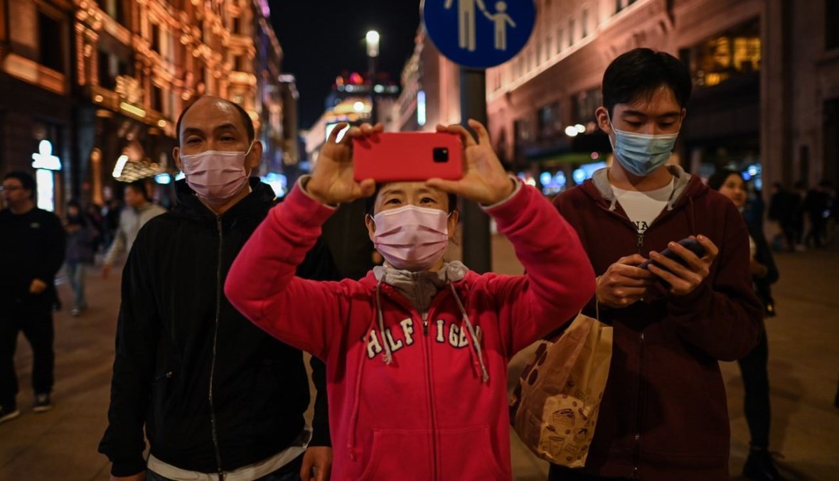 امرأة تلتقط صورة في شارع للمشاة في شنغهاي (23 ت1 2020، أ  ف ب). 