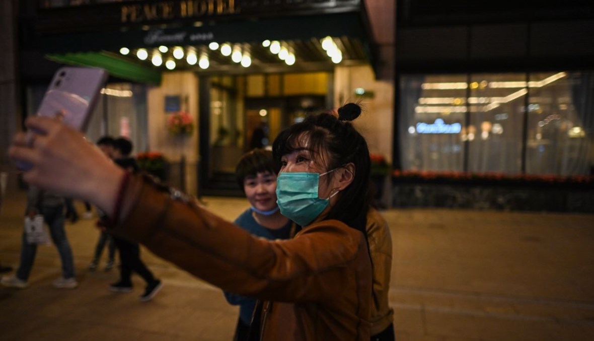 امرأة تلتقط صورة سيلفي في شارع للمشاة في شنغهاي (23 ت1 2020، أ ف ب). 