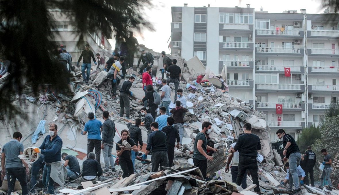 متطوعون يزيلون الأنقاض خلال بحثهم عن ناجين في مبنى منهار في إزمير بتركيا (30 ت1 2020، أ ف ب). 