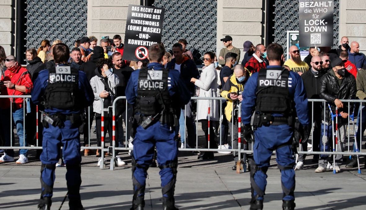 شرطيون يراقبون متظاهرين في برن خلال احتجاجهم على تدابير كورونا (31 ت1 2020، أ ف ب). 