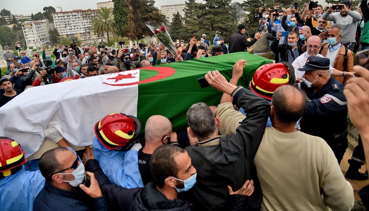 مشيعون يحملون نعش بورقعة خلال دفنه في مقبرة سيدي يحيى بالعاصمة الجزائر (5 ت2 2020، أ ف ب). 