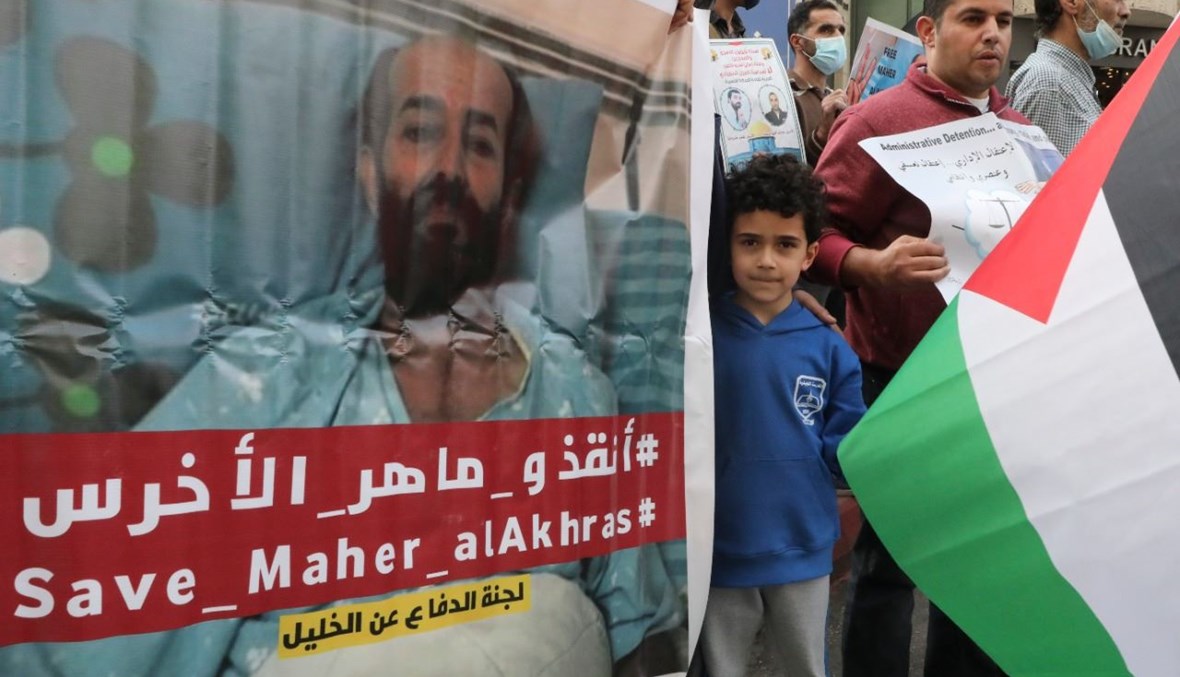 فلسطينيون يحملون لافتات تطالب بالإفراج عن الأخرس خلال تظاهرة في الخليل (3 ت2 2020، أ ف ب). 