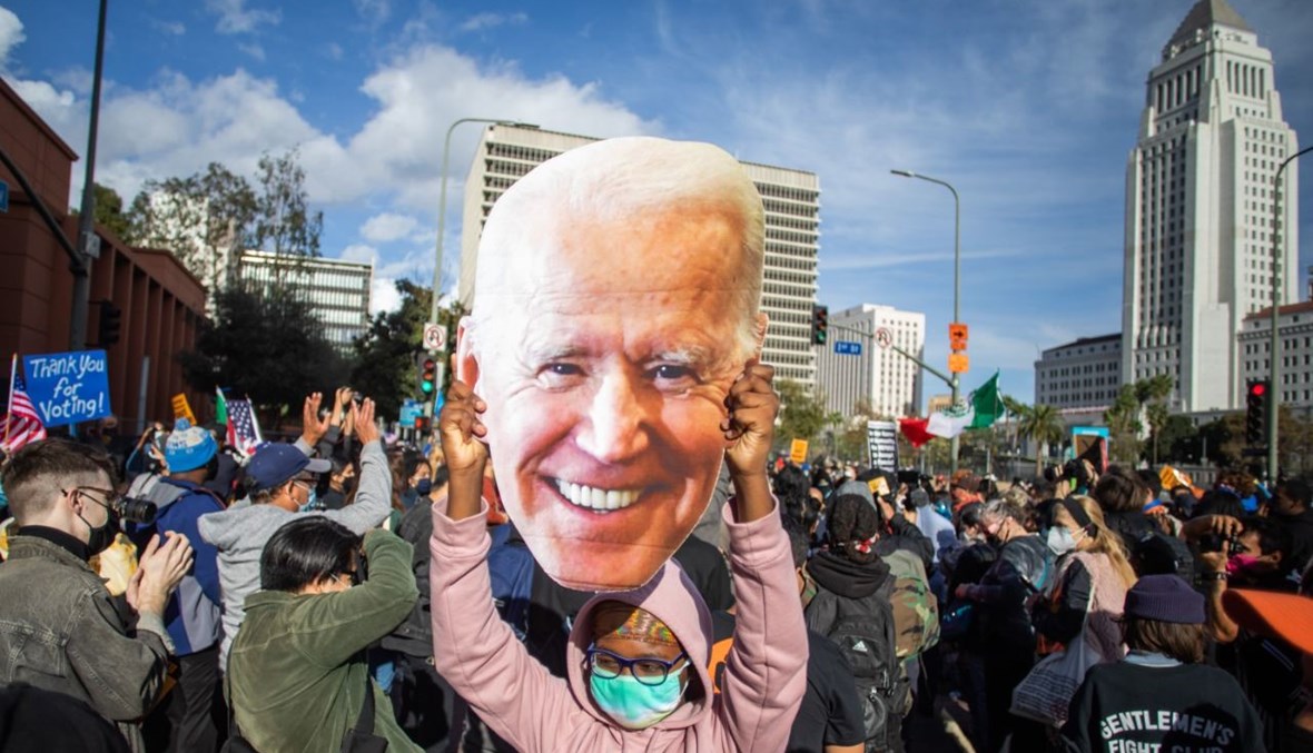 امرأة تحمل صورة بايدن خلال مسيرة في لوس انجليس احتفالا بفوزه (7 ت2 2020، أ ف ب). 