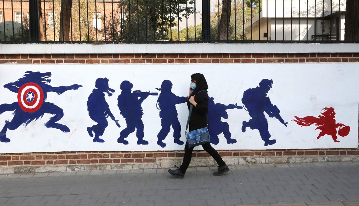 امرأة تمر بالقرب من جدارية مرسومة على الجدران الخارجية للمبنى السابق للسفارة الأميركية في طهران (4 ت2 2020، أ ف ب). 